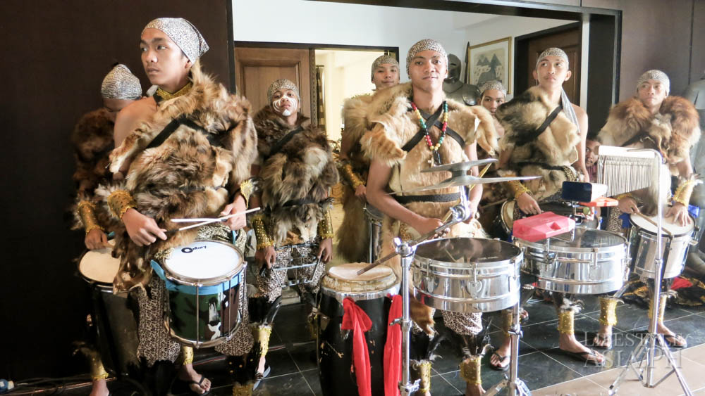 Men dressed in tribal costume and playing drums greeted guests