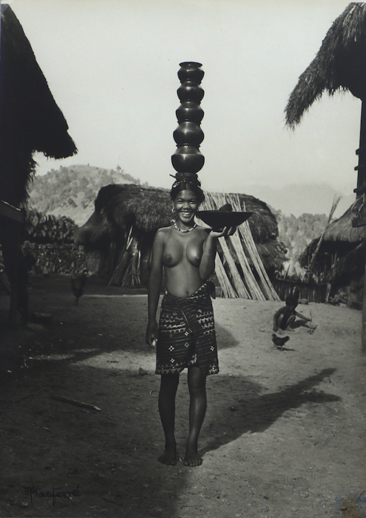 Water is carried home, sometimes from distant springs. In the background, rattan dries against a hous. Buscalan, Tinglayan, Kalinga. 1955 [Eduardo Masferre]