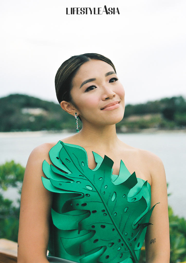 Smiling while wearing Emerald green top with cut-out leaf shape by Rosenthal Tee (made to order), emerald earrings by Mei Diamond Jewelry.