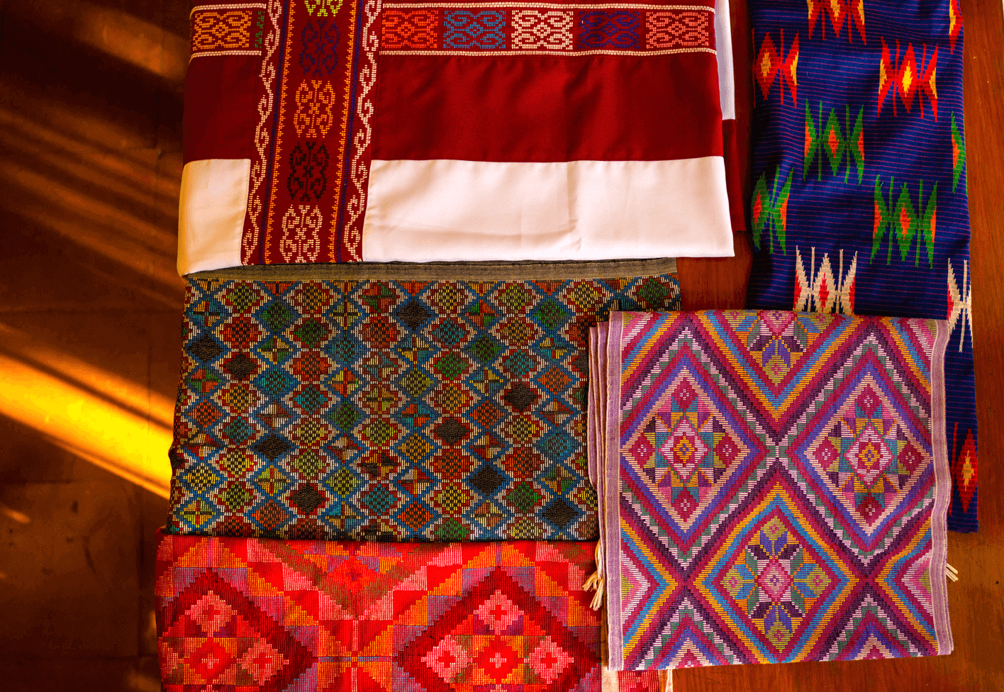 Green, purple, and red fabrics pictured at the bottom: Yakan "Seputangan" textiles; Blue fabric pictured at the right-most side: Tausug "Siyabit" textile; Red and white fabric at the top-most left: Maranao "Langkit" Malong