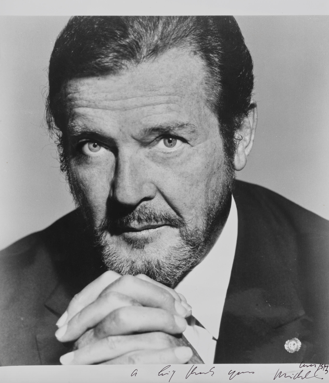 A large black and white portrait photograph of Sir Roger Moore