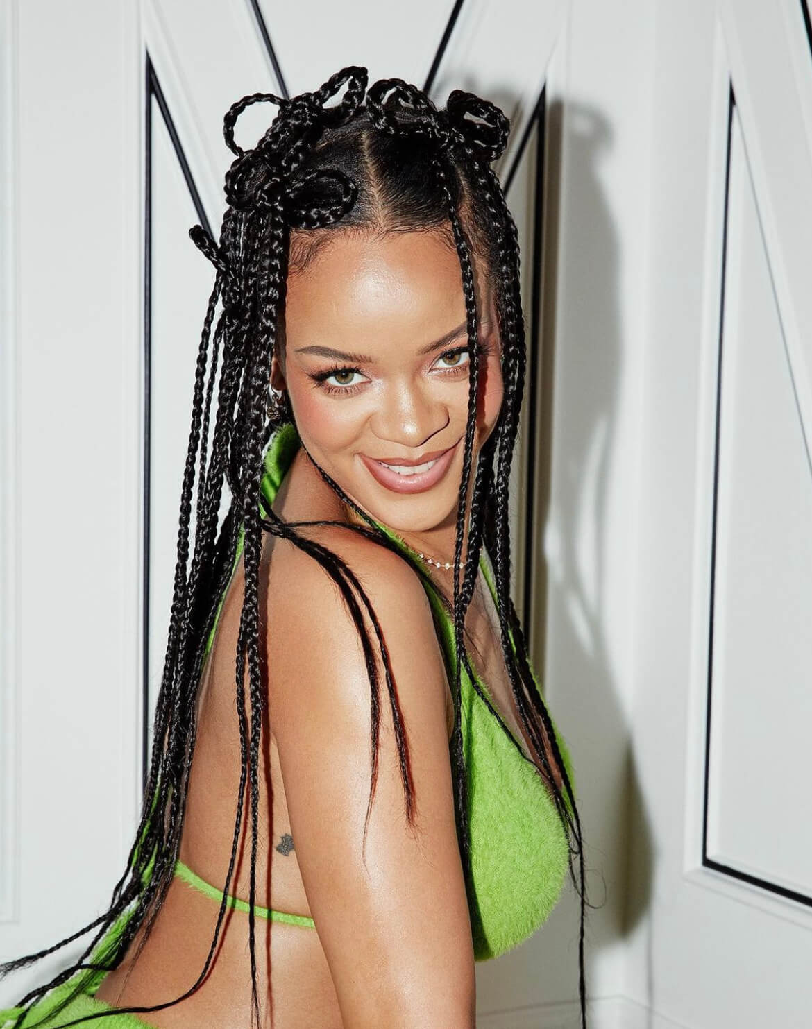Rihanna smiling at the camera, wearing a green two piece. She posted this on Instagram with a caption "it's cozy grinch season."