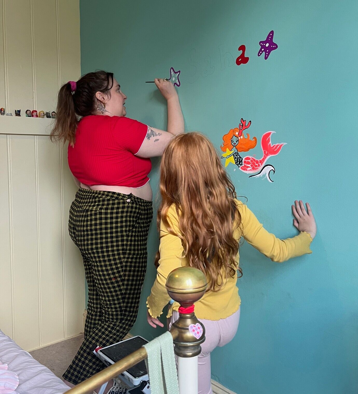 Lena Dunham painting a mural in a child's room.