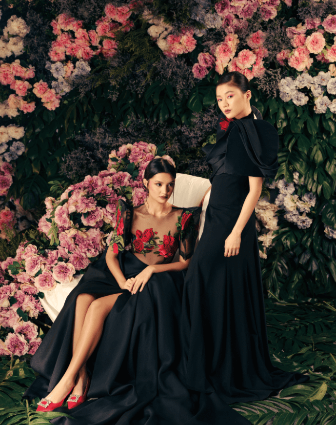 On Danielle: Modern terno of sheer tulle with gossamer terno sleeves and peau de soie silk draped skirt, accented with red roses and French embroidery accents; On Selina: Black crepe de chine column terno with sculptural peau de soie draping detail, and red rose neck piece, all by JO RUBIO. Red slingback heels, ROGER VIVIER.