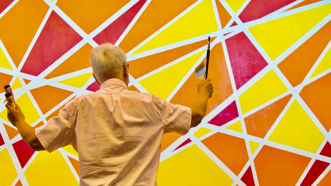 Cayabyab wielding his paintbrush in front of his mural “Directions” (10.6 x 17.6 feet, acrylic on canvas)