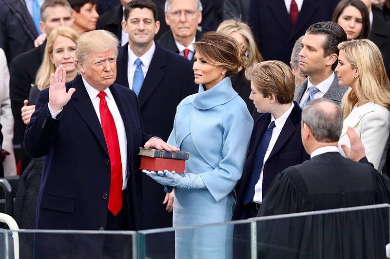 Former President Donald Trump being sworn in on January 20, 2017 at the U.S. Capitol building in Washington, D.C. Melania Trump wears a sky-blue cashmere Ralph Lauren ensemble. He holds his left hand on two versions of the Bible, one childhood Bible given to him by his mother, along with Abraham Lincoln’s Bible.