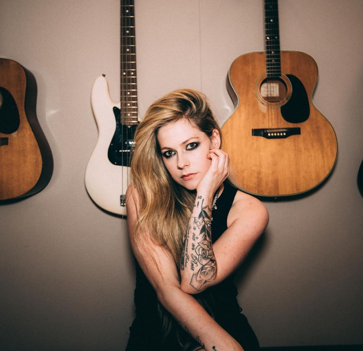 Avril Lavigne posing in front of her guitars. 