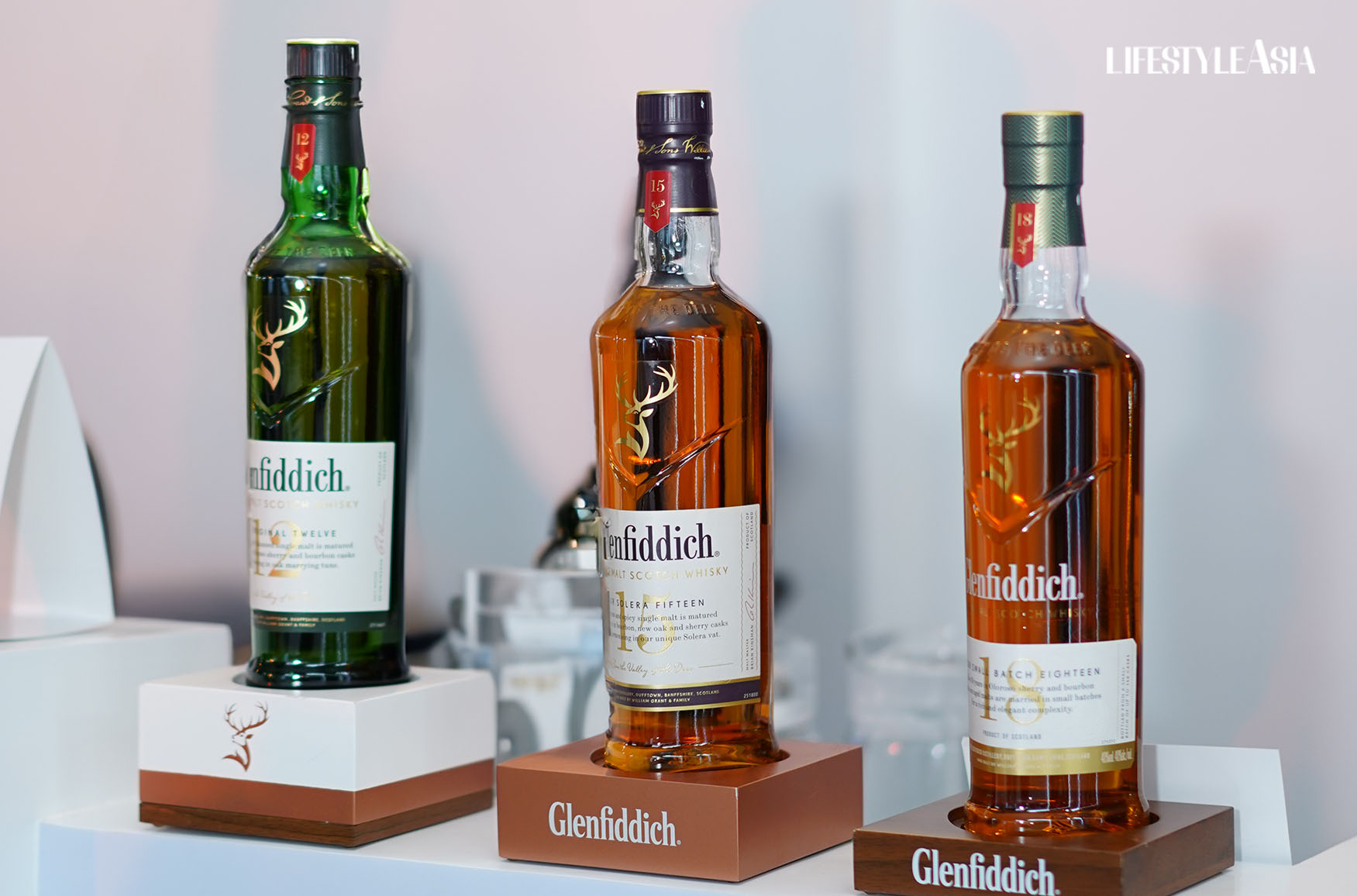 The Glenfiddich 12, 15, and 18 displayed on wooden bottle stands with Glenfiddich's glyph and trade name