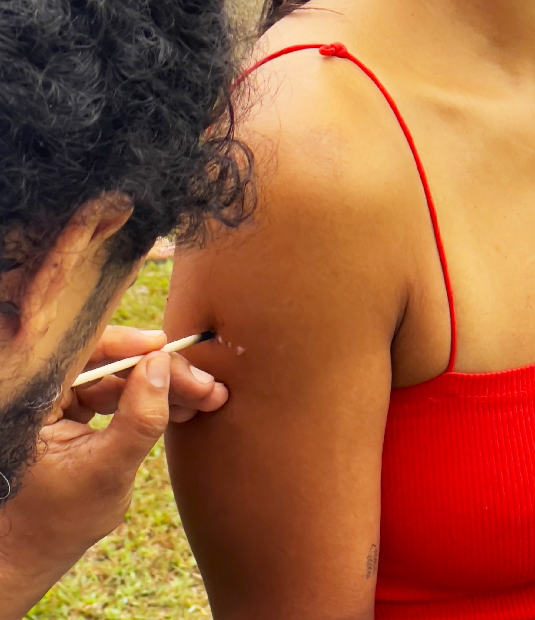 A facilitator inserts kambo or frog venom on a participant's skin