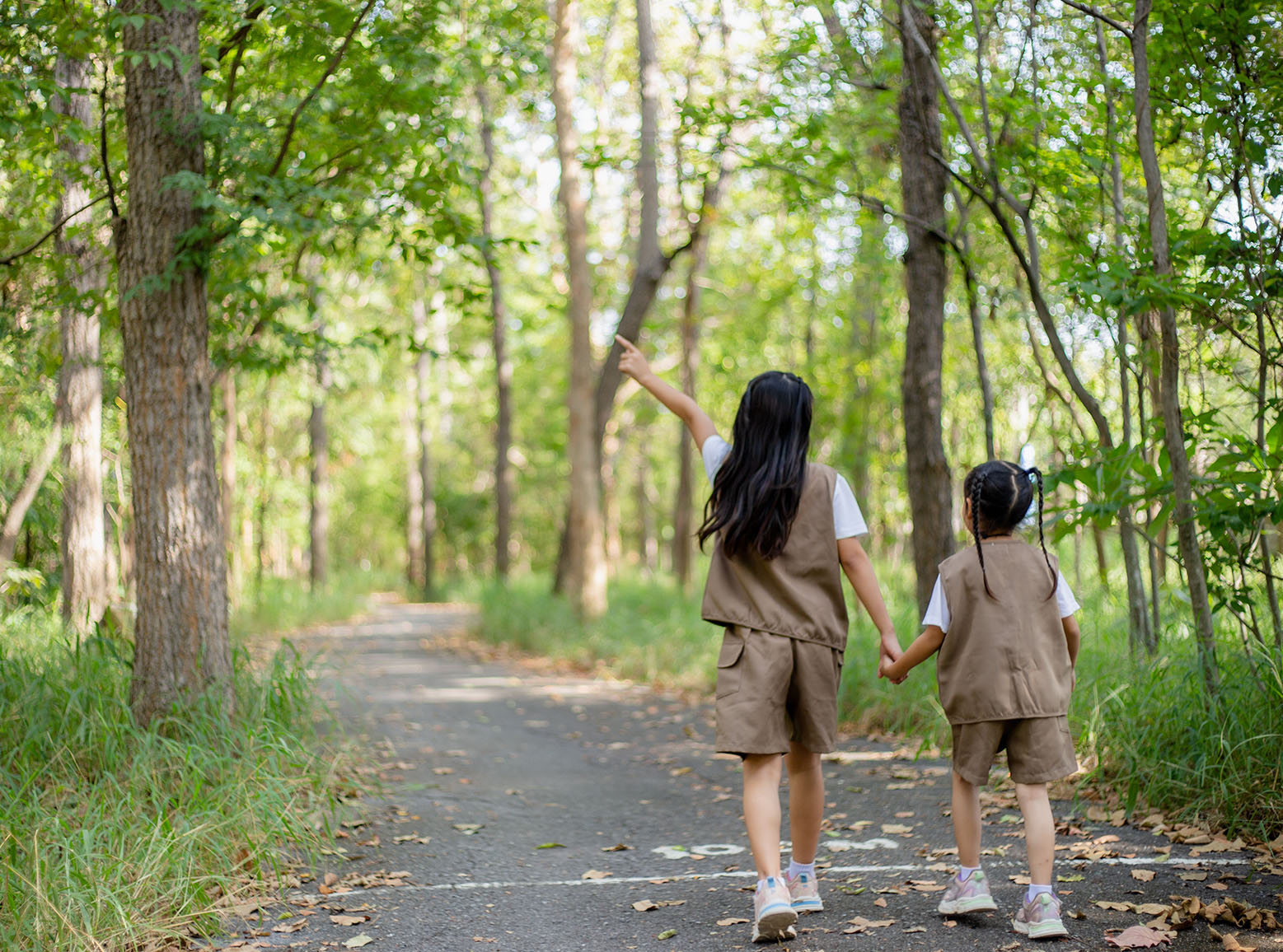 Two female kids walking hand-in-hand in the park